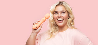 Woman with blonde hair smiling and holding VUSH Majesty 2 wand vibrator