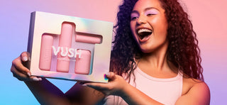 Woman with curly dark hair holding box of VUSH Pop Collection vibrators