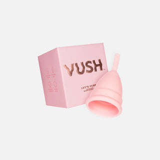 Pink square box that reads "VUSH LET'S FLOW REGULAR MENSTRUAL CUP" next to upside down pink menstrual cup against light grey background